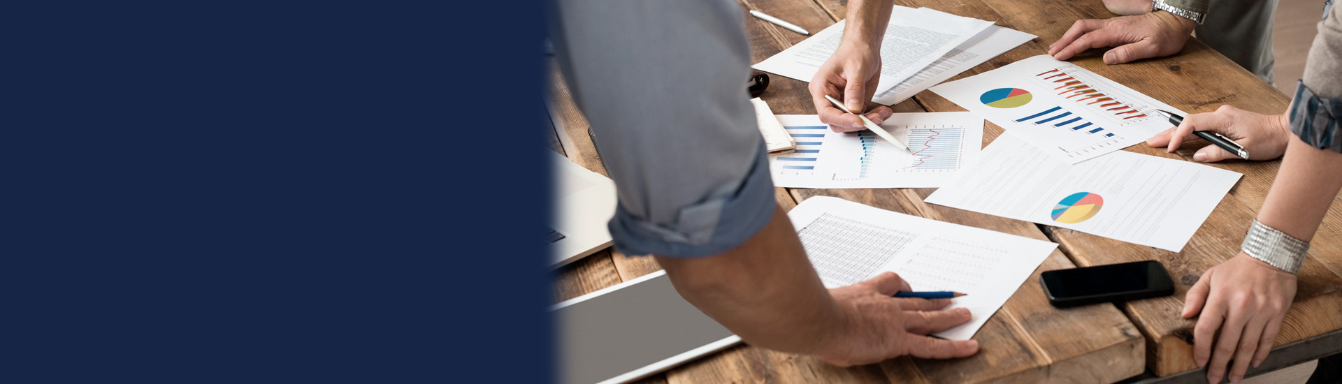 Grupo de personas analizando gráficos sobre una mesa Grupo de personas analizando gráficos sobre una mesa