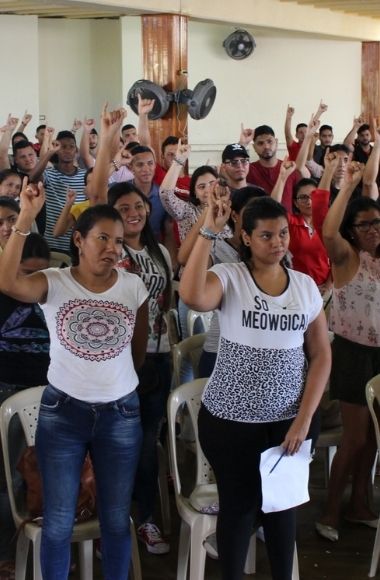 Grupo de personas con el brazo derecho alzado.