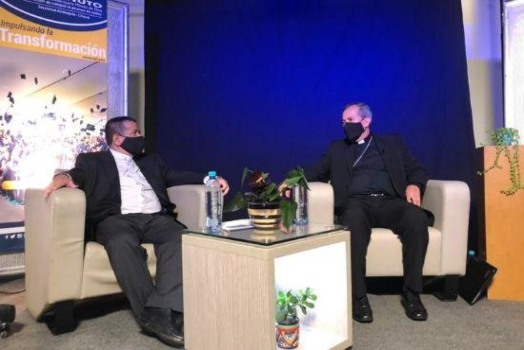 Dos personas sentadas en sofá y con distanciamiento, en diálogo academico (Rector UNIMINUTO Bello y Arzobispo de Medellín) 