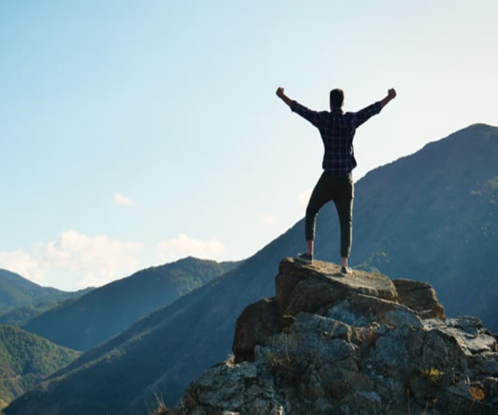 hombre en la cima de una montaña extendiendo sus brazos