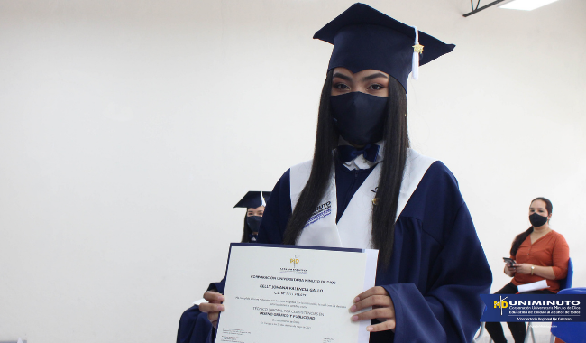 Estudiantes sentados  con toga en la ceremonia con su diploma