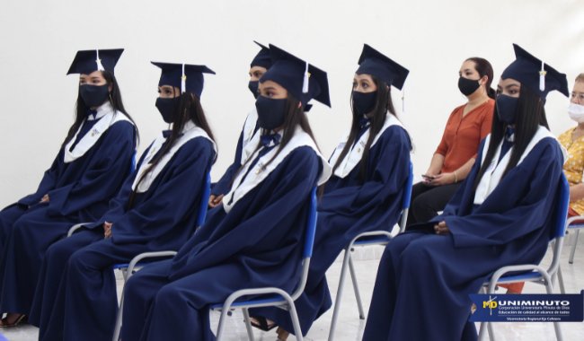 Estudiantes sentados  con toga en la ceremonia