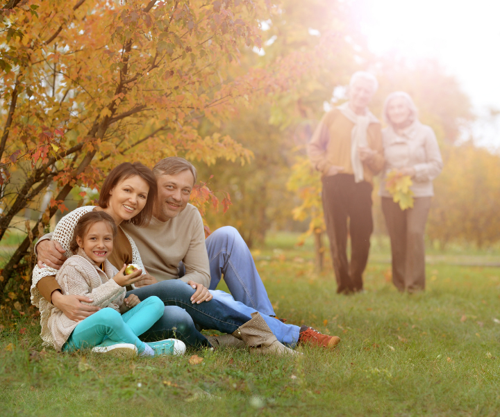  Familia comparte en el parque, sentados en el pasto sonrien. 