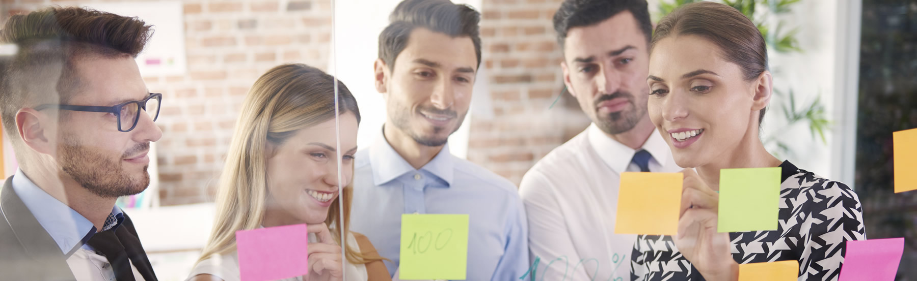 Mujer líder con grupo de trabajo, realizando actividad con posit