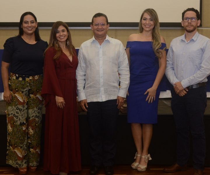 Dos mujeres y un hombre de pie posando a la cámara 