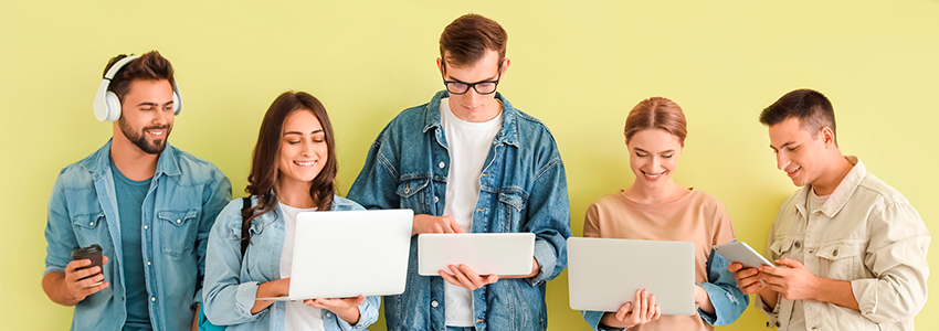 Estudiantes con dispositivos modernos cerca de la pared de color verde, buscando Proyectos sociales de formación