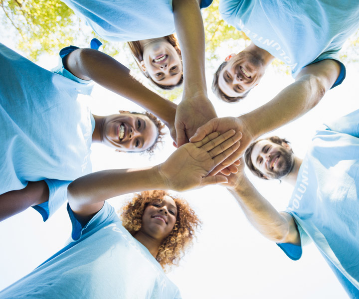 Grupo de personas de camiseta azul uniendo las manos en el centro