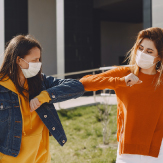 Dos estudiantes mujeres se saludan con el codo. 