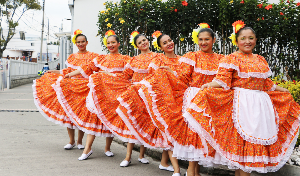 Mujeres en fila, con traje típico, posando para la cámara. 