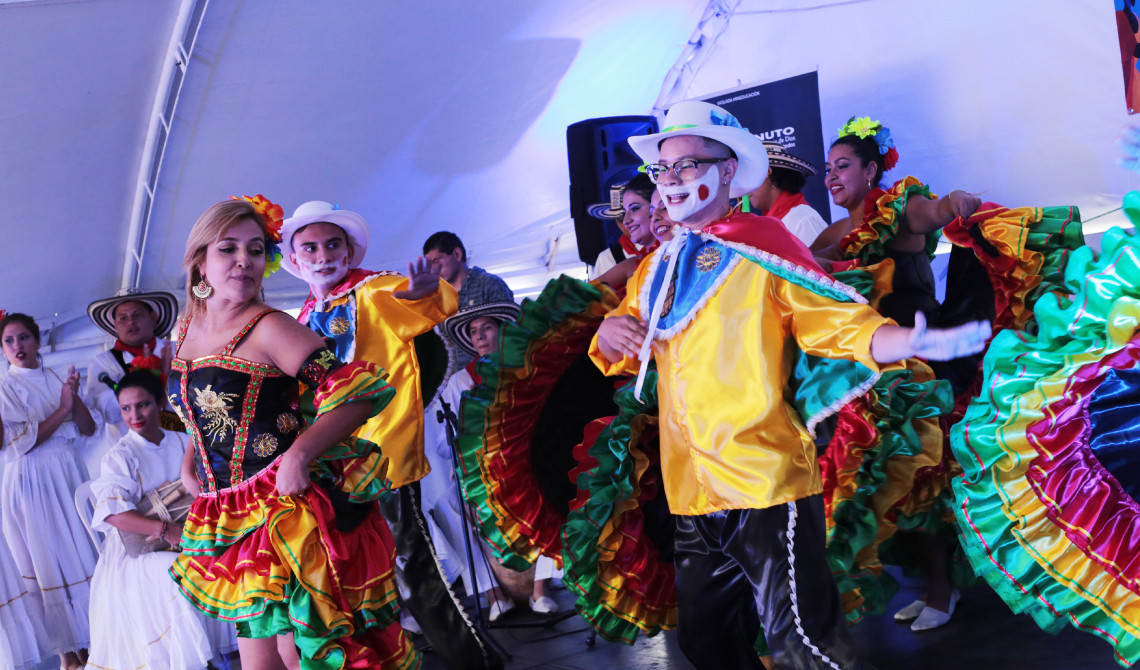 Grupo musical animando a un grupo de baile de colorido vestuario.