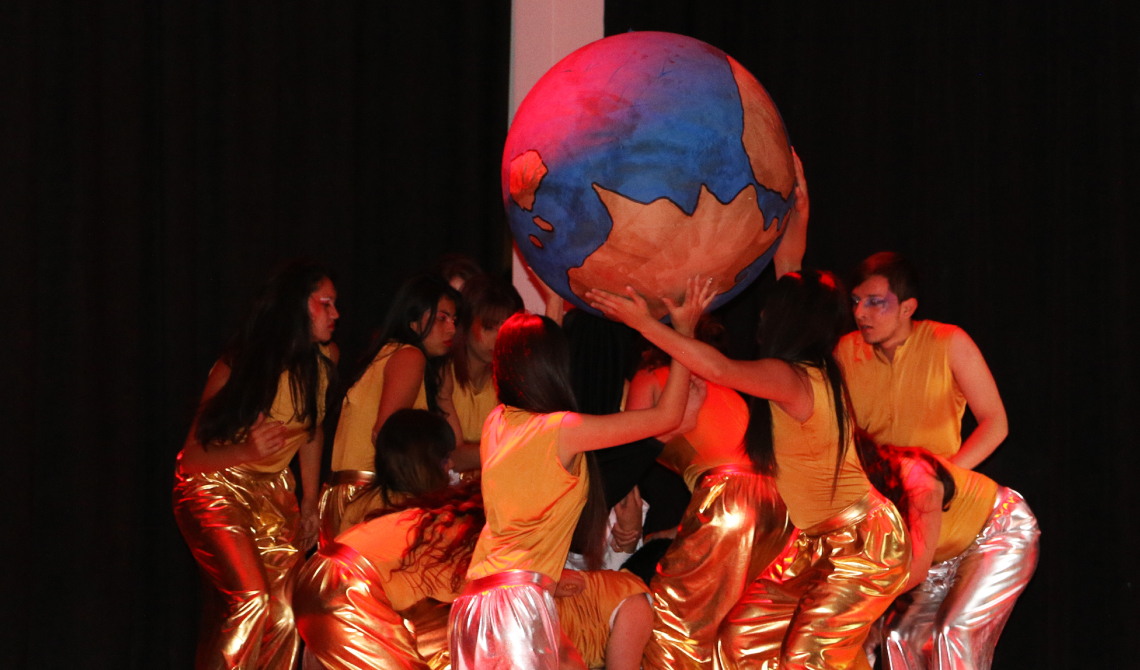 Grupo de danza sosteniendo un gran globo terráqueo.