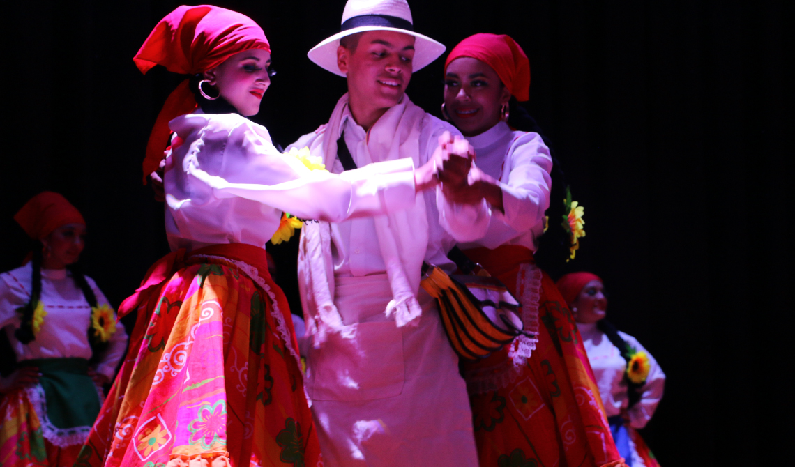 Tres estudiantes bailando en el centro del escenario. 