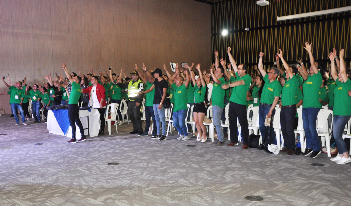 Todos de pie y con los brazos arriba en el auditorio, disfrutando de las presentaciones.