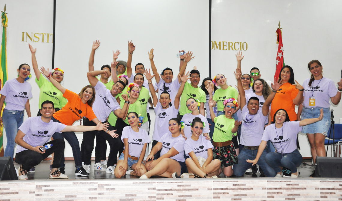 Grupo numeroso de estudiantes y colaboradores con los brazos arriba, posando para la cámara. 