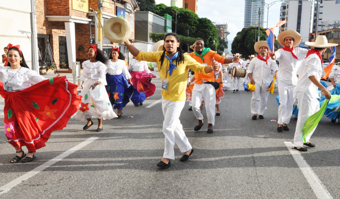 Grupo de danza bailando en tres filas por la calle principal.