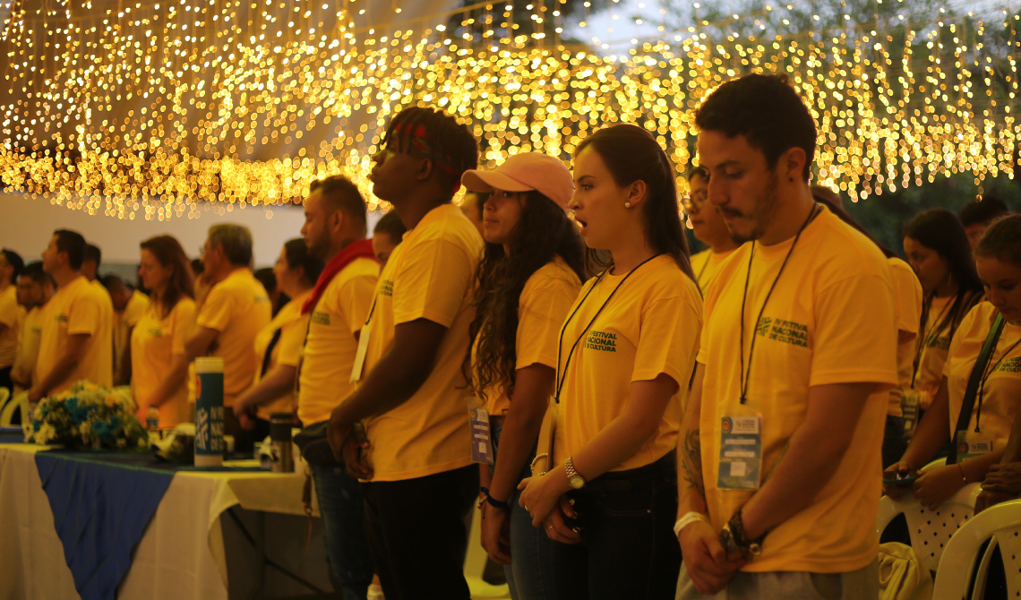 Estudiantes con camisetas amarillas escuchando atentos la oración de bienvenida.