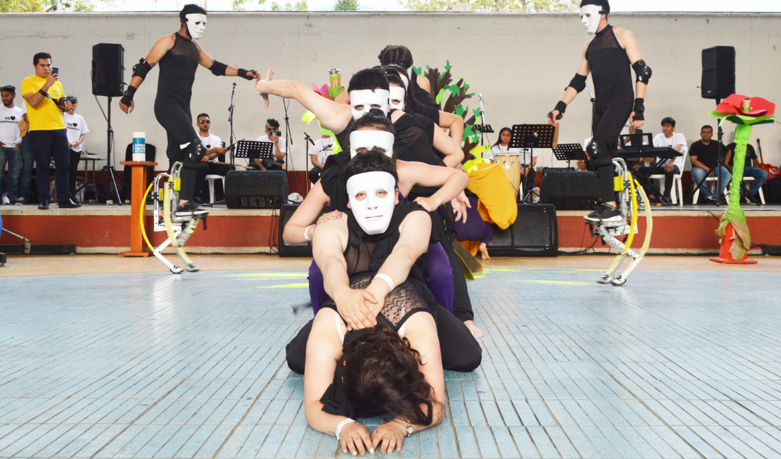 Grupo de danza y teatro con máscaras blancas, en medio de su presentación.