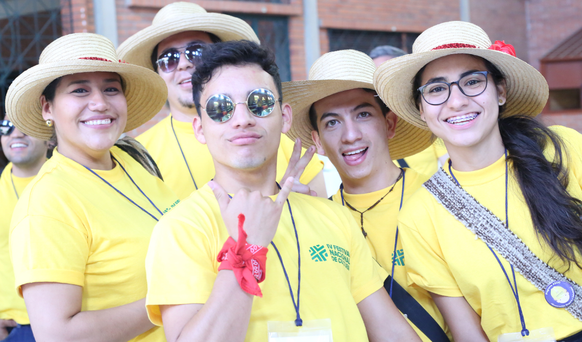 Cinco estudiantes con camiseta amarilla, posando alegres para la cámara.