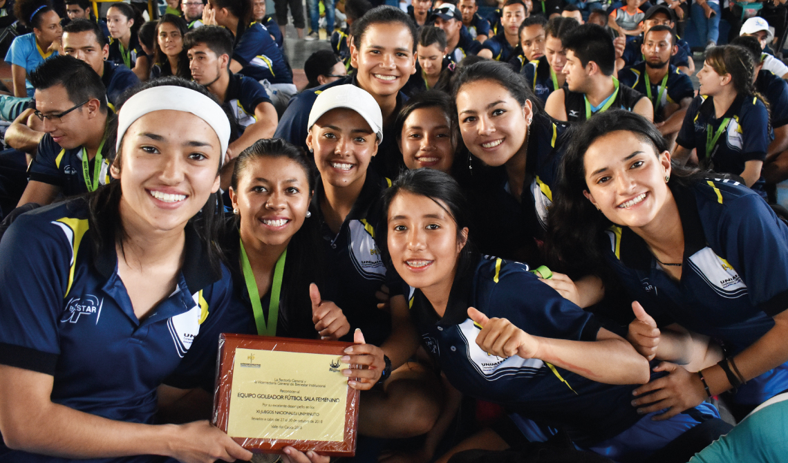 Equipo de futbol sala femenino sonriendo con su placa de reconocimiento. 