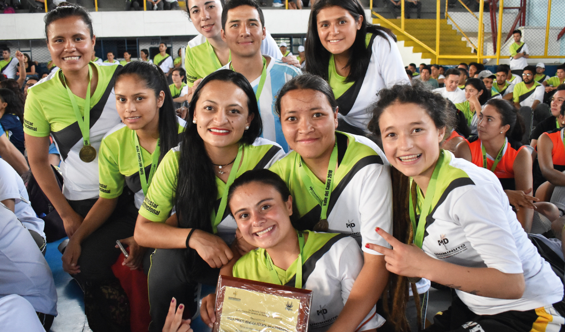 Equipo de futbol sala femenino sonriendo con su placa de reconocimiento.