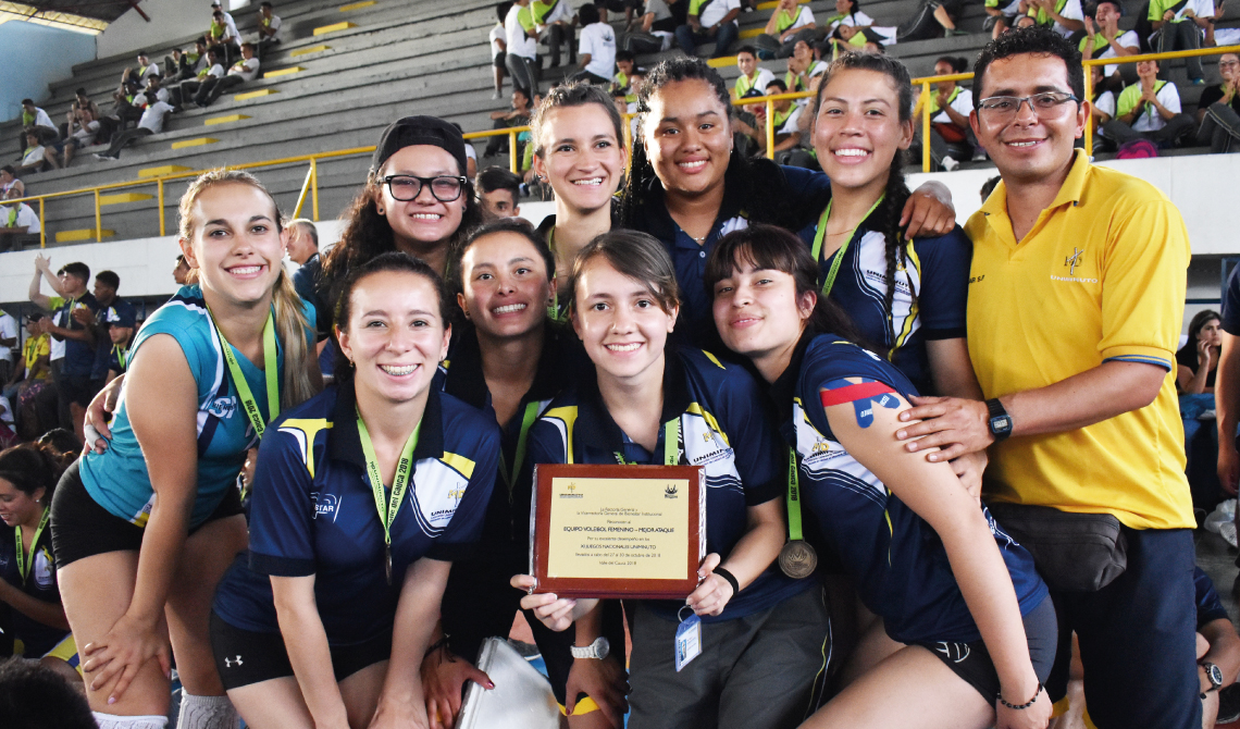 Equipo de voleibol femenino sonriendo con su placa de reconocimiento.