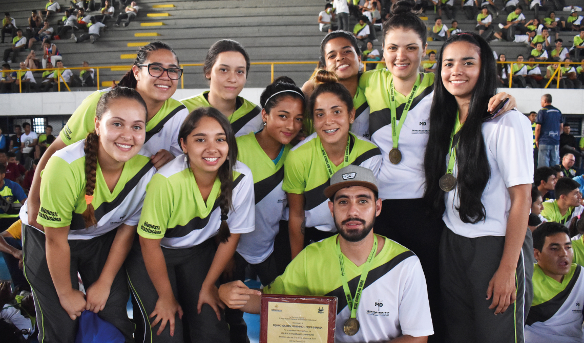 Equipo de voleibol femenino sonriendo con su placa de reconocimiento.