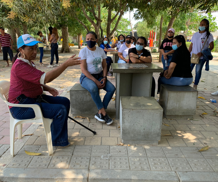 Mujer hablándole a varios jóvenes en una plaza 