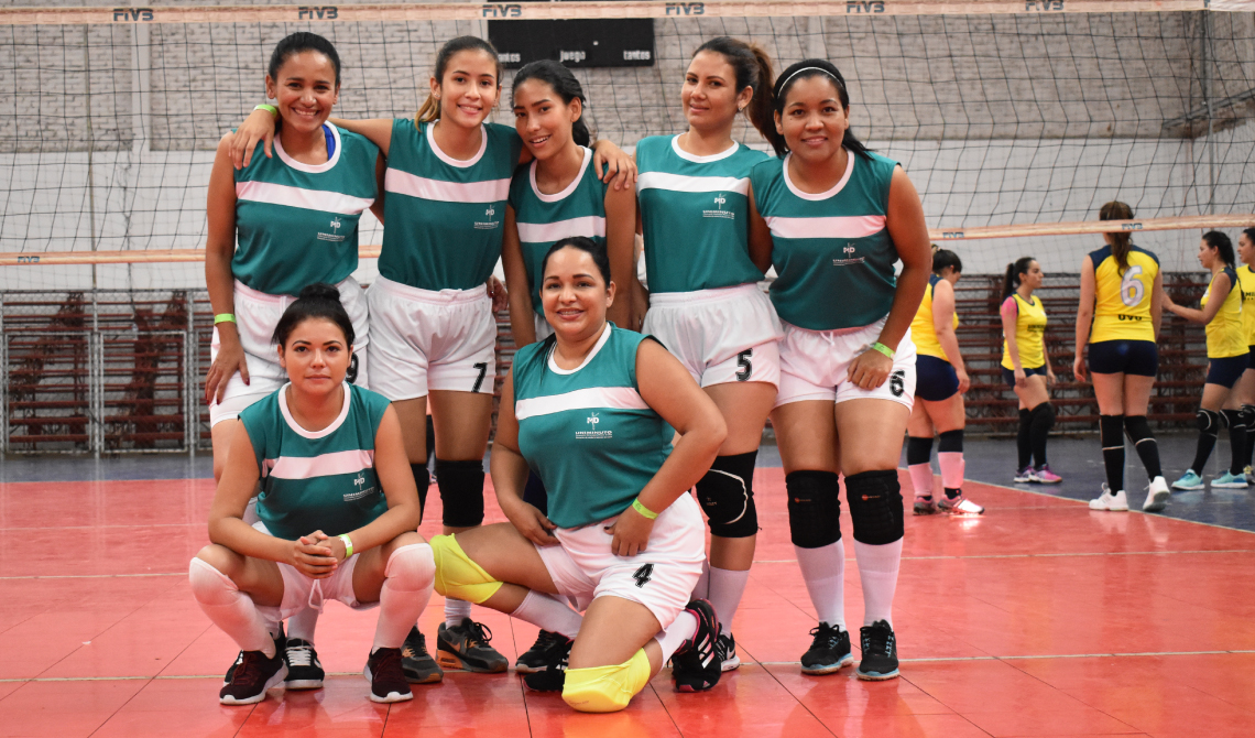 Equipo femenino de voleibol posando para la cámara antes de competir.