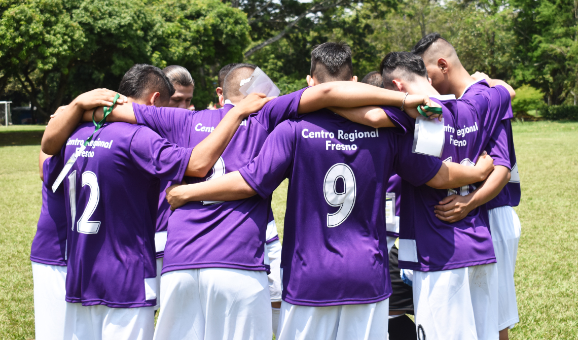 Equipo de fútbol masculino del Centro Regional Fresno, orando antes de competir.