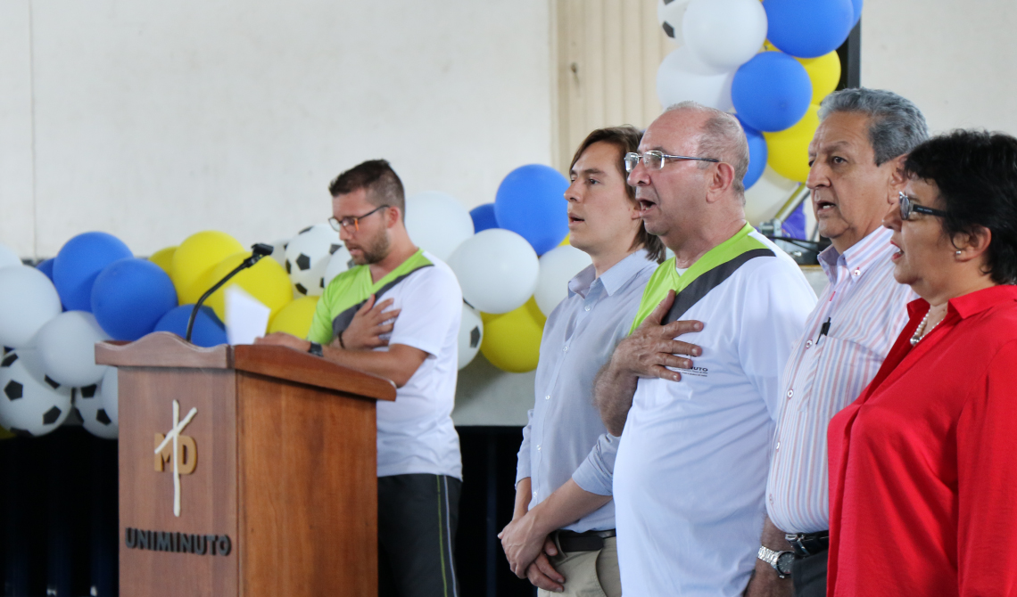 Colaboradores de UNIMINUTO cantando el himno nacional.