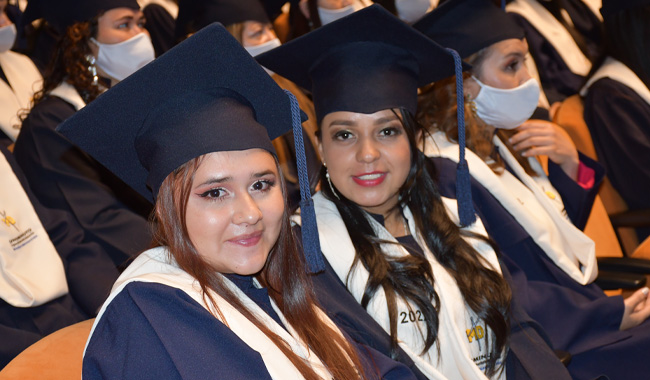 Dos estudiantes mujeres esperando ser llamadas para recibir su diploma de graduación