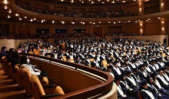Escenario de graduación con estudiantes sentados - toma lateral