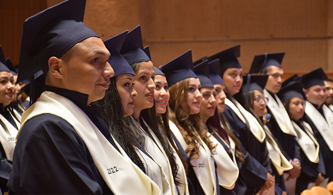 Fila de estudiantes en sus sillas esperando ser llamados a recibir diplomas de graduación