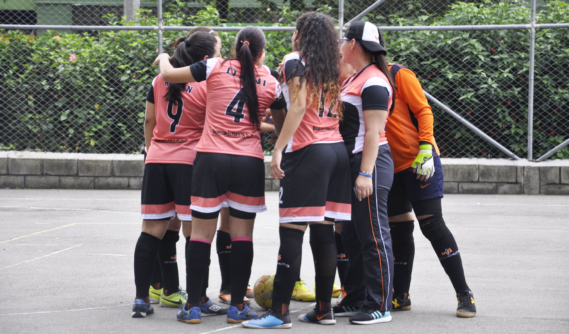 Equipo de fútbol sala femenino uniendo sus manos, antes de comenzar el juego.