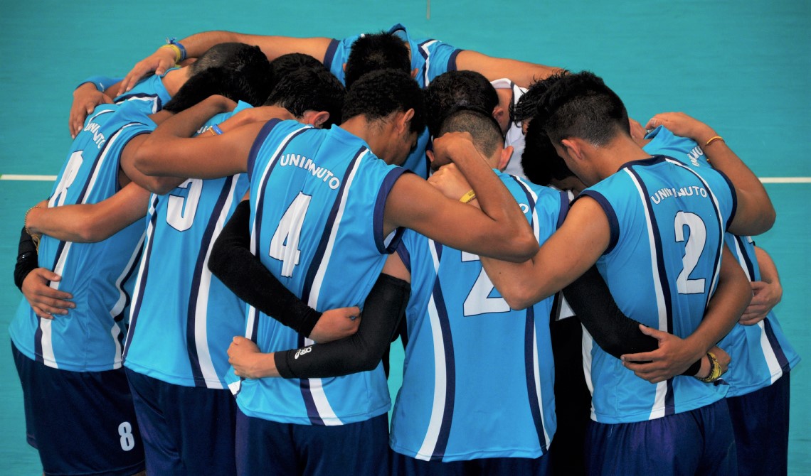 Equipo de voleibol masculino orando antes de iniciar el juego. 