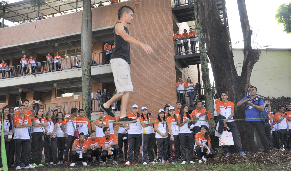 Joven caminando sobre una cuerda en medio de los asistentes.