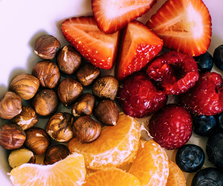 Guía para tener una alimentación saludable Fresas, frambuesas, arándanos, mandarina y maíz tostado en un plato.