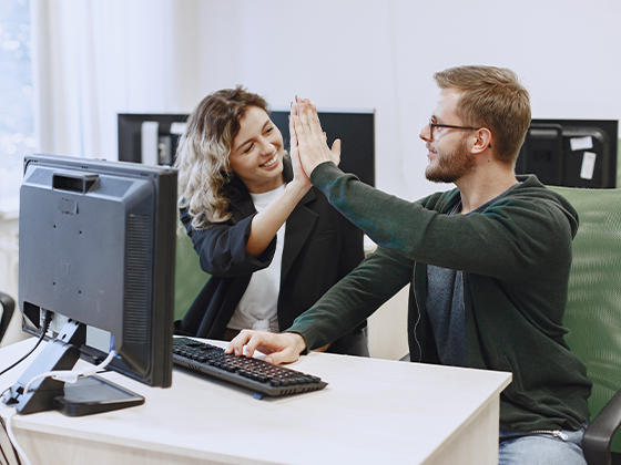 Estudiantes chocando las manos frente al computador