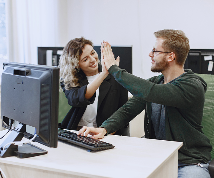 Estudiantes chocando las manos frente al computador