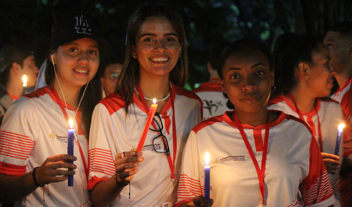 Tres estudiantes alegres con una vela en sus manos