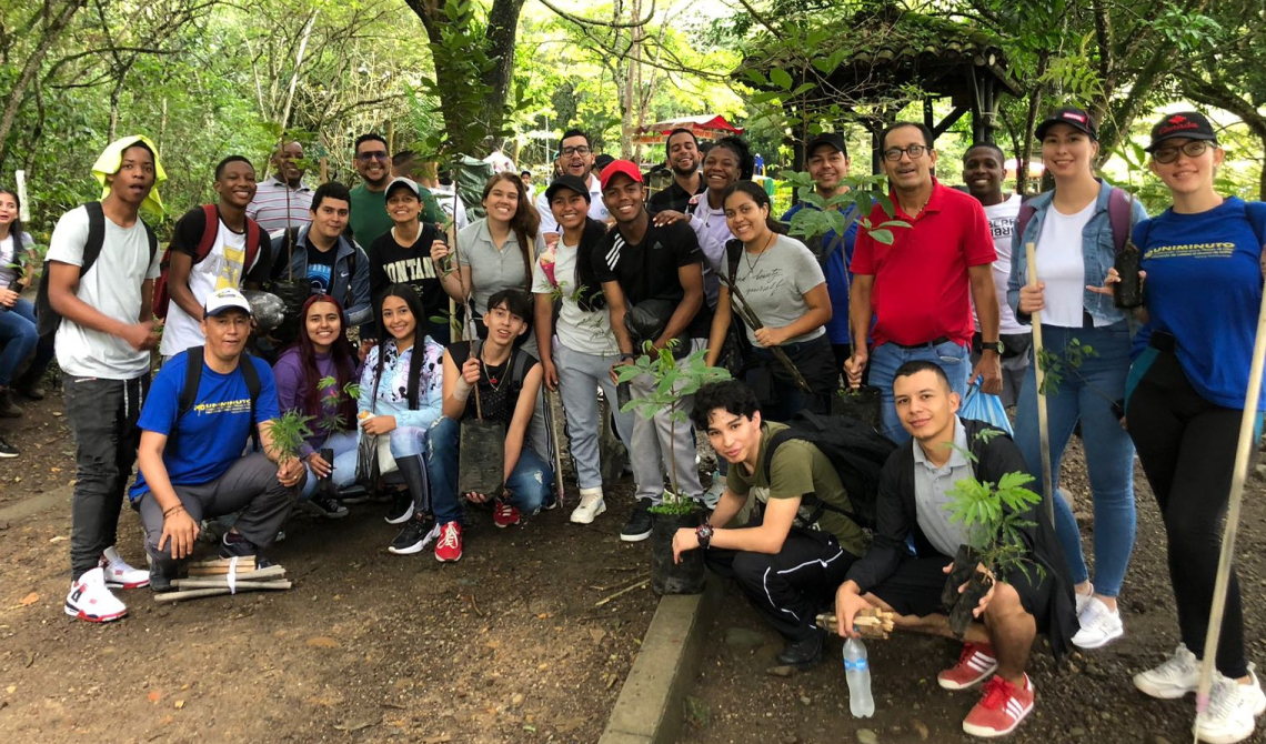 Grupo de personas alegres con árboles para sembrar.