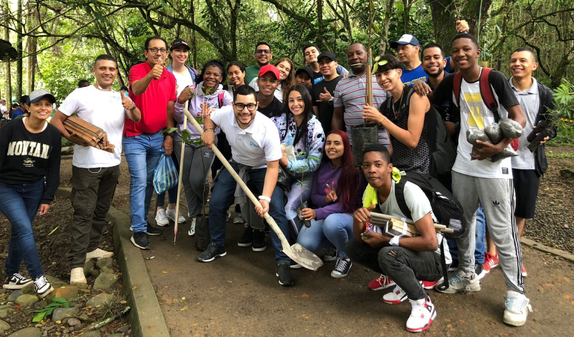 Grupo de personas alegres con árboles para sembrar.