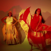 Dos mujeres con vestidos representativos bailando folclore.