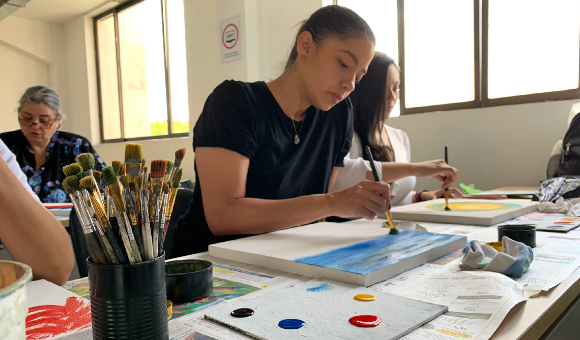 Estudiante mujer pintando concentrada en el lienzo.