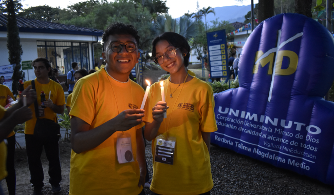Estudiantes sonrientes con una vela prendida en sus manos