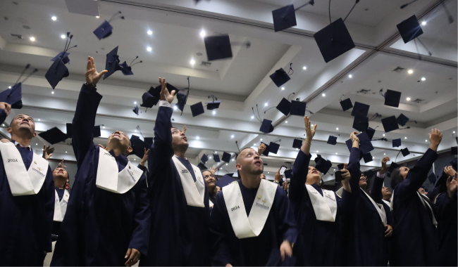 Estudiantes graduandos lanzando birretes al aire