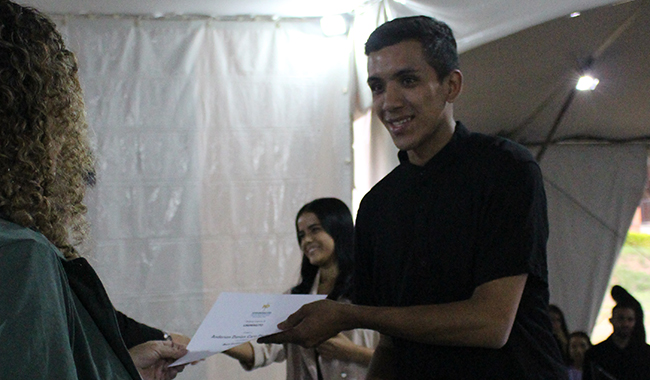Estudiante recibiendo su certificado de beca en el escenario