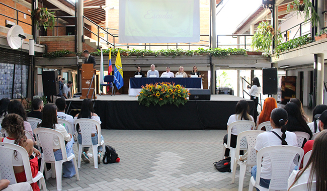 Estudiantes escuchando las palabras del presentador de ceremonia. 