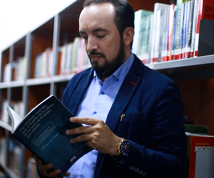 Profesor Miguel Barreto de UNIMINUTO sosteniendo el libro “Una estrategia curricular para el fomento de la cultura de las paces en el ámbito universitario”
