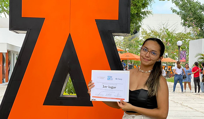 Estudiante ganadora del concurso junto al logo de la Universidad Anáhuac de Cancún de México.
